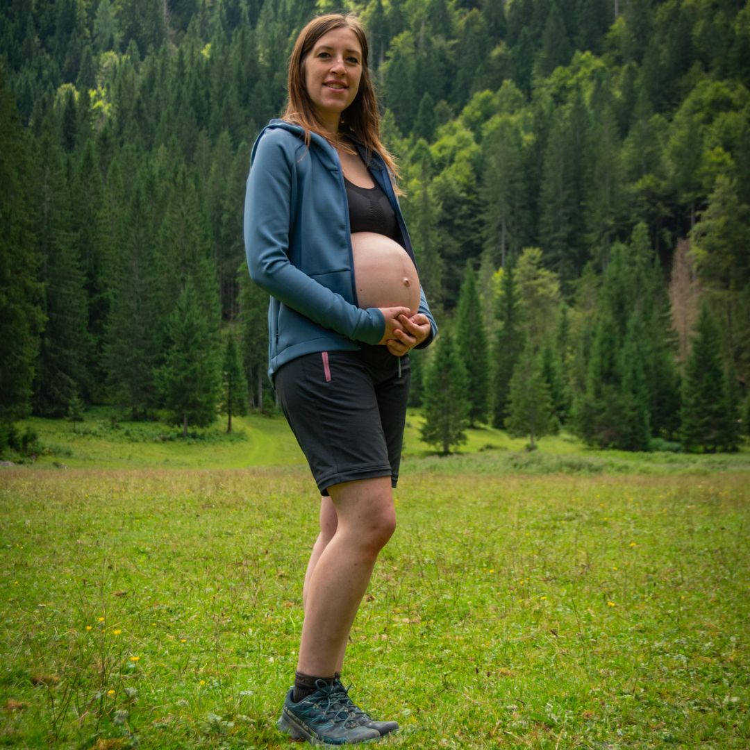 donna incinta in una radura montana
