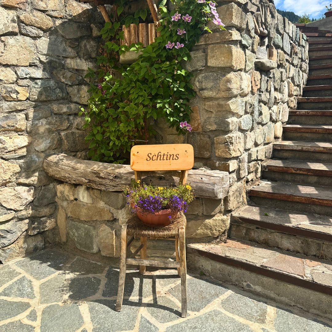 Scorcio di Sappada con una sedia in legno con vaso fioriti